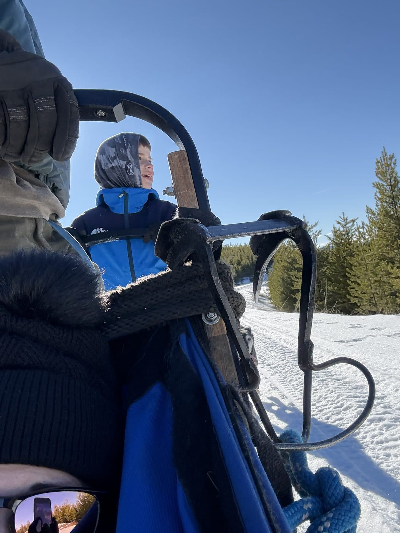 Stephanie’s son bundled up on a dog sled on a bright winter morning in Montana