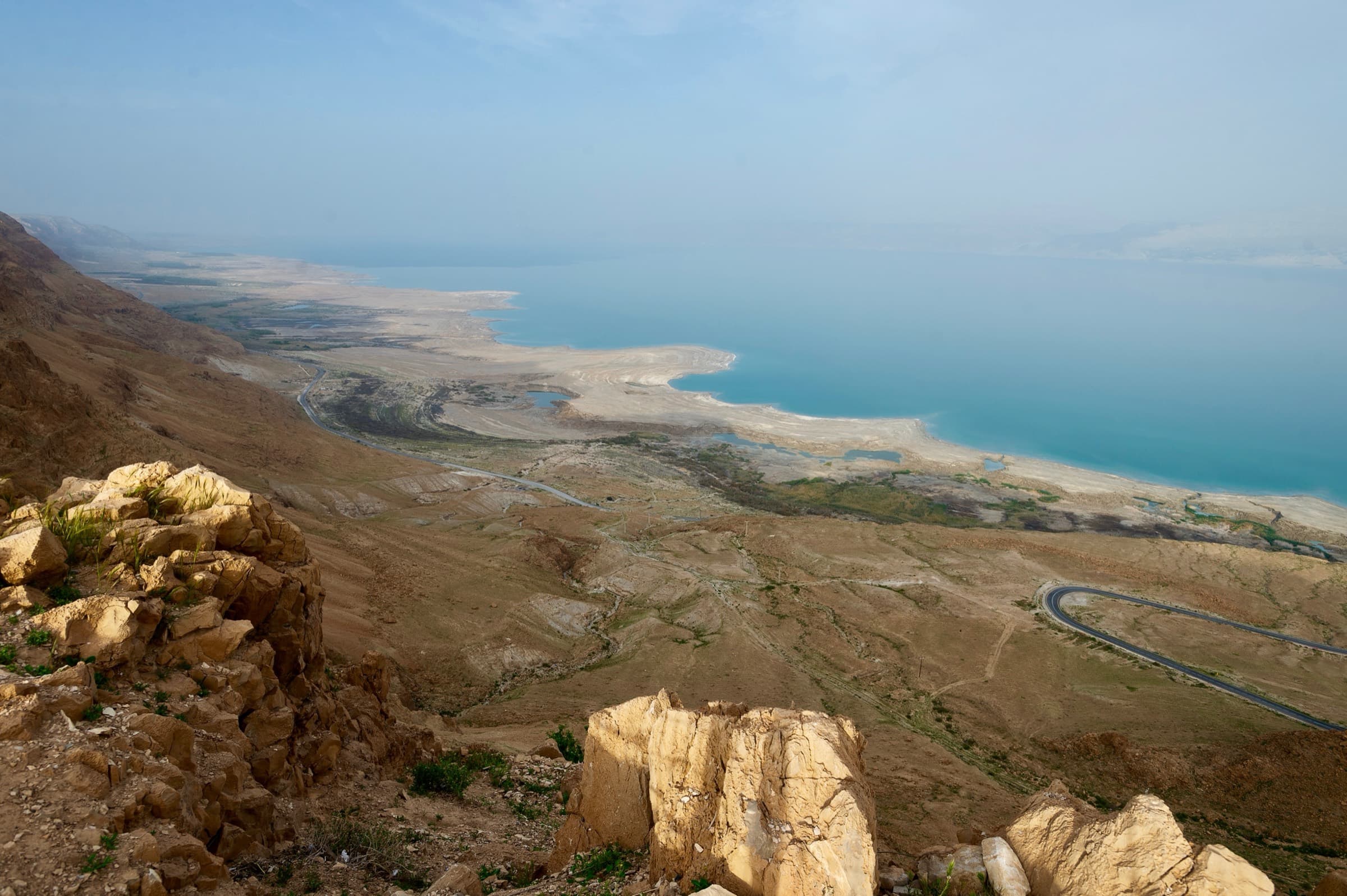 The Dead Sea stretching beyond the desert cliffs of Masada, seen from above